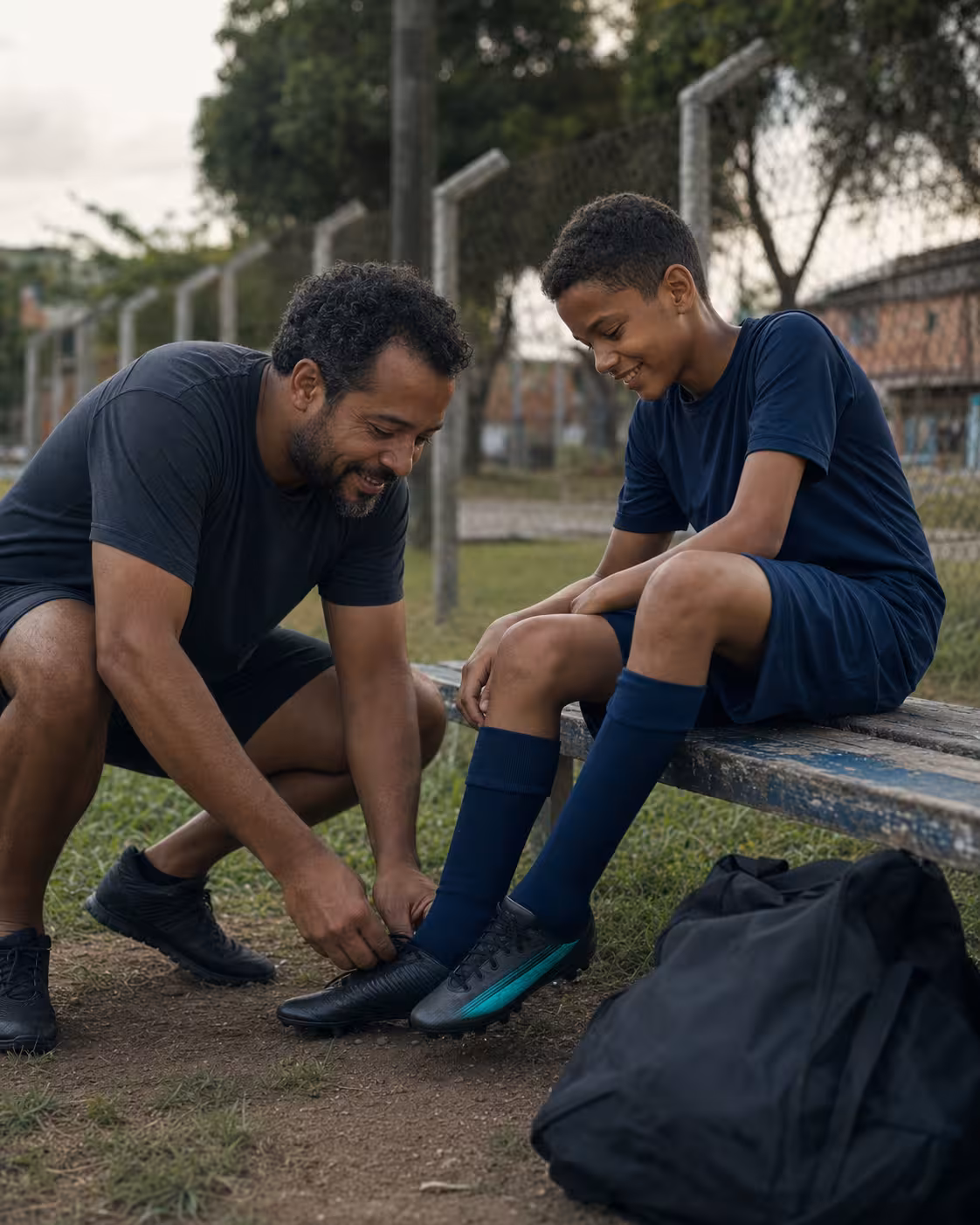 Pai ajudando o filho com a chuteira após o treino
